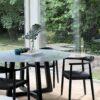 Betover je interieur met onze ronde "Nox" tafel, voorzien van een luxueus Bianco Carrara marmeren blad met een diameter van 150cm en ondersteund door een prachtig gekruist houten onderstel